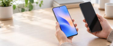 Hands compare two smartphones on a bright desk